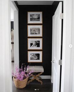 a hallway with pictures on the wall and a basket full of flowers in front of it