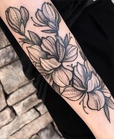 a black and white photo of a flower tattoo on the left arm, with leaves in it