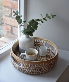 a white vase sitting on top of a wooden tray next to a cup and saucer