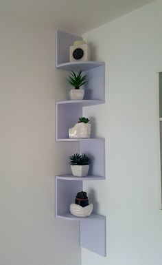 three white shelves with plants on them against a wall