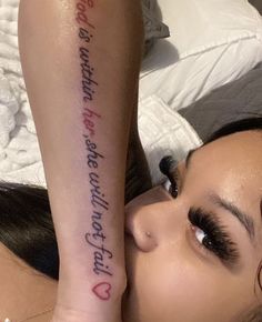 a woman laying on top of a bed next to her arm with writing on it