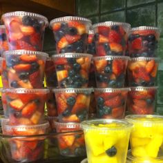 plastic cups filled with fruit sitting on top of a counter next to other containers full of fruit