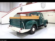 an old green pick up truck parked in a garage