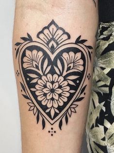 a black and white heart tattoo on the right arm, with an intricate design in the middle