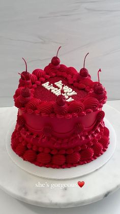 a heart shaped red cake on a white plate with the word love spelled in it