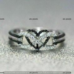 a heart shaped diamond ring sitting on top of a silver surface with sparkles around it