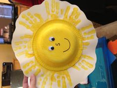 a paper plate with a smiley face painted on the center and hands holding it up