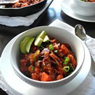 two white bowls filled with food sitting on top of a table next to silverware