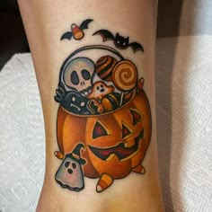 a person with a halloween themed tattoo on their leg and foot is holding a pumpkin