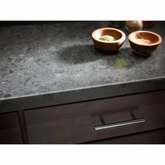 two wooden bowls sitting on top of a counter next to a metal drawer and drawers