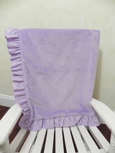 a purple blanket sitting on top of a white wooden chair in front of a wall