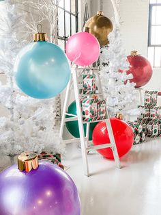 a white christmas tree with lots of colorful balls hanging from it's branches and decorations