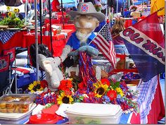 a table topped with lots of food and stuffed animals in front of an american flag tent