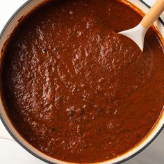 a pot full of red sauce with a wooden spoon in the top and bottom half