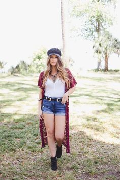 a woman standing in the grass wearing shorts and a hat