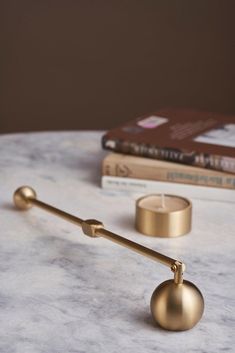 a gold candle holder on a marble table with books and a book in the background