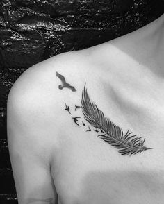 a black and white photo of a woman's chest with a feather tattoo on it