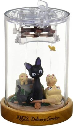 a black cat in a glass case with other figurines around it on a wooden base