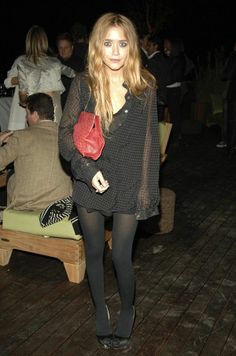 a woman standing on a wooden floor holding a red purse