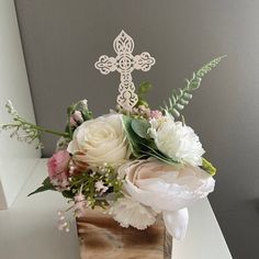 a bouquet of flowers in a wooden box on a table with a cross above it