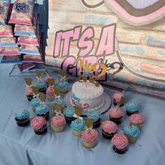 cupcakes are arranged on a table with a cake and other treats in front of it