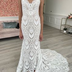 a woman in a white wedding dress standing on a wooden floor next to a couch