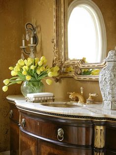 a vase filled with yellow flowers sitting on top of a wooden dresser next to a mirror