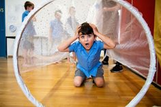 a young boy sitting on the floor in front of a white net while holding his hands to his head