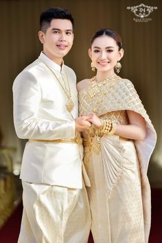 two people standing next to each other wearing white outfits and holding hands in front of them