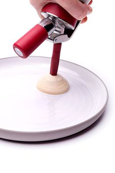 a person is using a pair of scissors to cut something on a white plate with a red handle