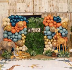 an elephant and giraffe stand in front of a backdrop made out of balloons