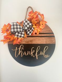 a wooden sign that says, thank you and is hanging on the wall with fall leaves