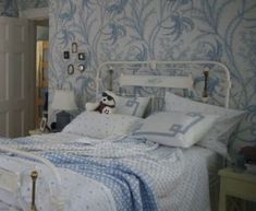 a bed with blue and white wallpaper in a bedroom