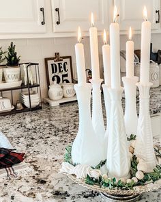 a bunch of white candles sitting on top of a counter