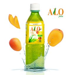 a bottle of alo juice with mangoes and oranges in the water next to it