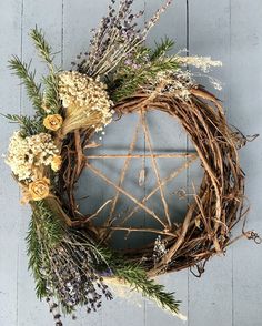 a wreath with dried flowers and greenery hanging on a wall