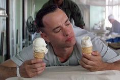 a man eating ice cream while laying on the floor in front of him with his eyes closed