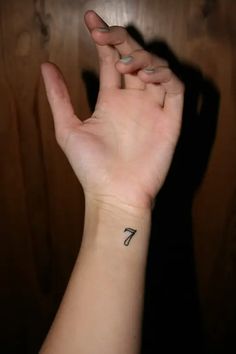 a person's hand with a small arrow tattoo on the middle of their wrist