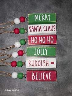 four wooden christmas signs with santa claus, holly, rudolph and believe written on them