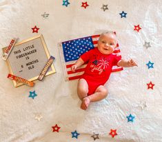 a baby laying on top of a bed next to an american flag and a plaque