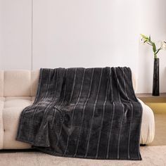 a couch with a blanket on top of it in front of a white wall and floor