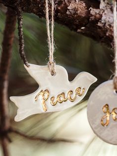 two ornaments hanging from a tree with the word peace written on them and an ornament in the shape of a dove