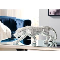 a glass table topped with a silver animal figurine next to a blue couch