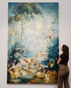 a woman standing in front of a large painting