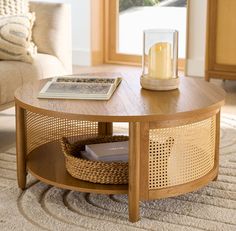 a coffee table with a basket underneath it and a candle in the middle on top