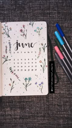 a notebook with the word june written on it next to some markers and pencils