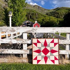 a red and white quilt sitting on top of a wooden fence