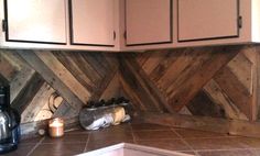 a kitchen with wooden walls and tile flooring on the counter top, next to a coffee maker