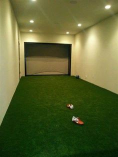 an empty room with fake grass and shoes on the floor