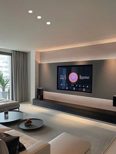 a living room with a large flat screen tv on the wall and couches in front of it